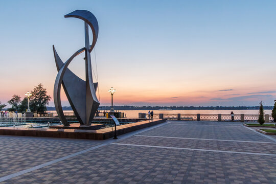 Sail sculpture on riverside promenade at sunset