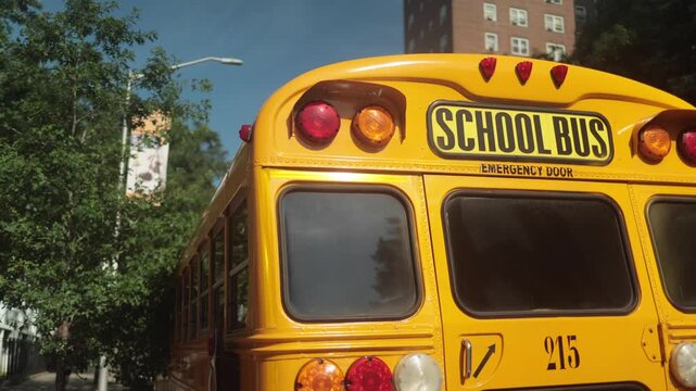 Yellow school bus driving down a new york city street with students inside, representing american education, public transportation, and everyday life in a sunny urban setting