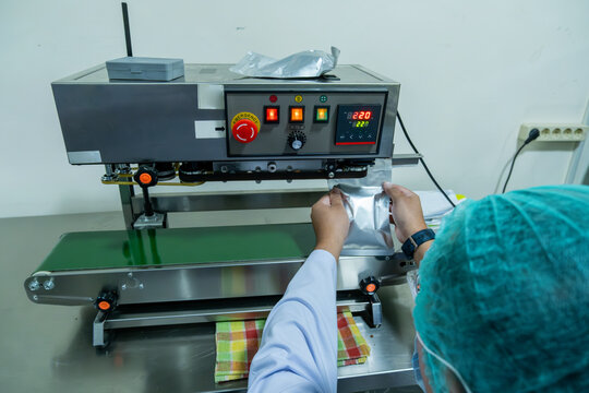 Worker operating packaging machine from overhead view in industrial processing room, production workflow concept.