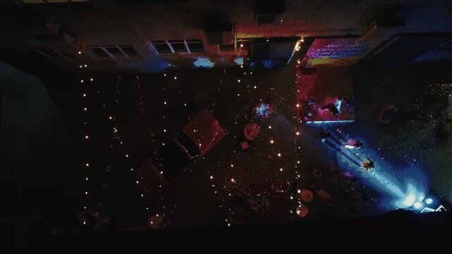 Top-down drone shot of an outdoor wedding party at night with string lights and a vintage car, ideal for wedding, event, and hospitality brand campaigns.