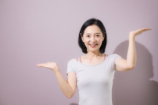 A middle-aged Japanese woman with her arms outstretched, comparing two options; a smiling woman explaining the differences between sports-related products and services