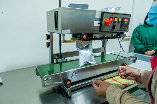 Worker operating packaging machine from overhead view in industrial processing room, production workflow concept.