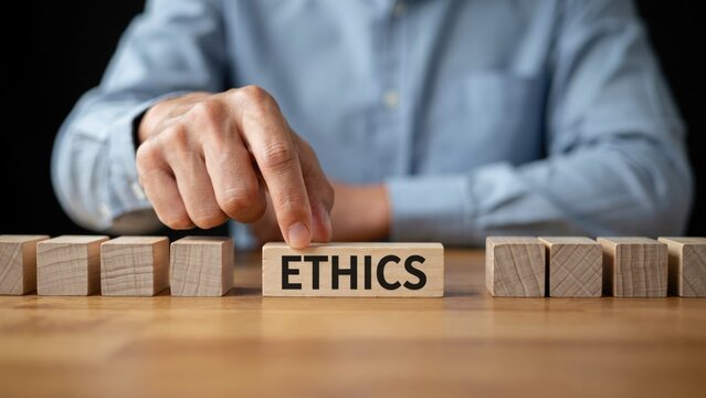 Hand placing a wooden block with the word ethics on a table