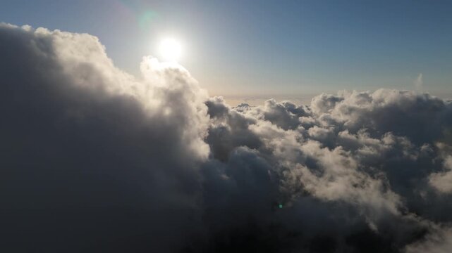 An aerial drone view showing thick white and gray clouds with bright sunlight filtering through the sky above Falougha, Lebanon.