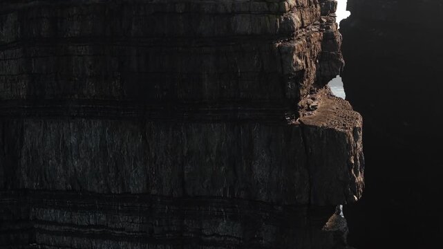 Sheer rock cliffs at Loop Head with Atlantic waves visible through a narrow gap