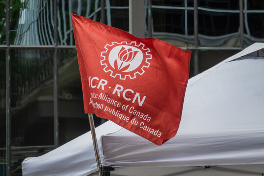 Ottawa, ON, Canada - Sept 14, 2026: Public Service Alliance of Canada red union flag waving on a white tent outside a building.