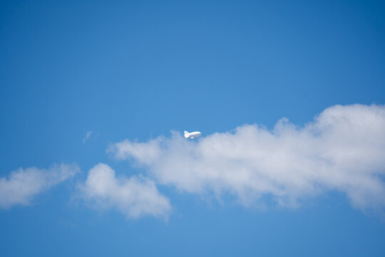 Tethered aerostat floating on blue sky with white clouds, helium surveillance balloon, high altitude monitoring airship