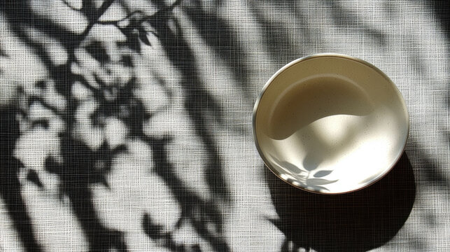 Serene Bowl with Nature Shadow Play on Textured Fabric Background