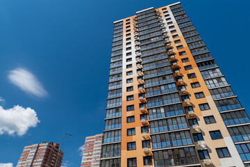 Fototapeta premium Building stands tall against a blue sky with clouds and other buildings in the background during the day