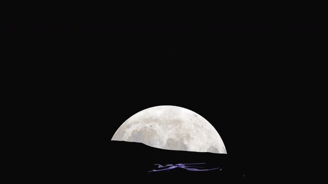 A full moon slowly rises against the backdrop of stormy ocean waves, with the moonlight reflecting on the water.