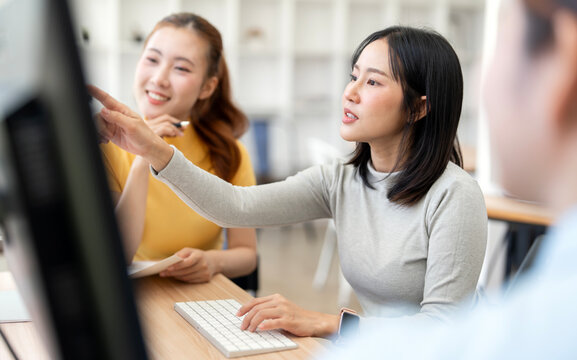 Asian Businesswomen Looking at Computer Screen and Discussing Project