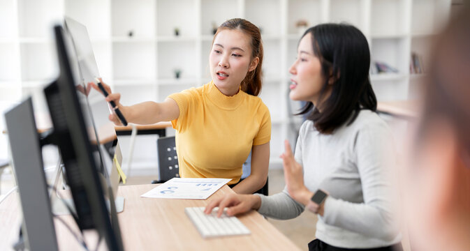 Asian Businesswoman Pointing Pen at Computer Monitor in Office Meeting