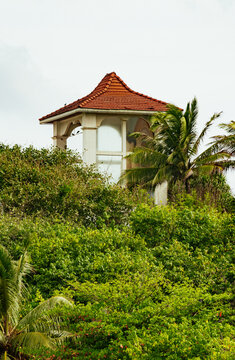 Traditional pavilion with red clay tile roof emerging from tropical foliage in Sri Lanka