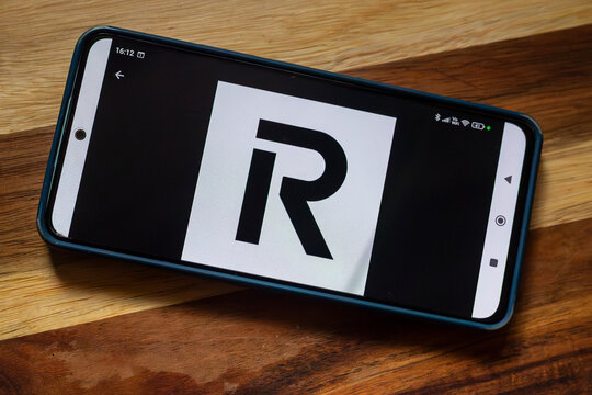 A smartphone lying on a wooden surface displaying the Revolut logo on its screen