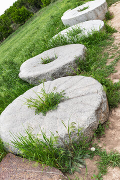 Ancient stone millstones among green grass at near the Burana Tower in Kyrgyzstan.