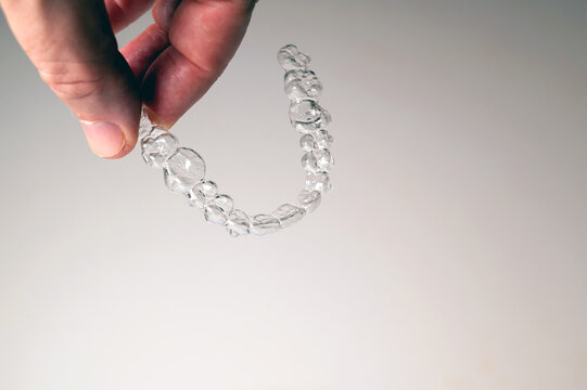 Hand holding clear aligner for teeth straightening treatment with copy space