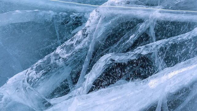 Video of abstract textured natural ice background of frozen Baikal Lake in cold winter day. Blue ice surface with pattern of white cracks. Natural ice backdrop. Mock up, copy space, Christmas blank
