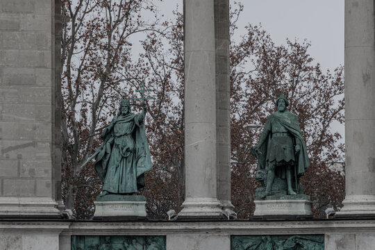 Statues of Hungarian kings Saint Stephen and Saint Ladislaus flanked by stone columns at Heroes Square colonnade in Budapest during winter.