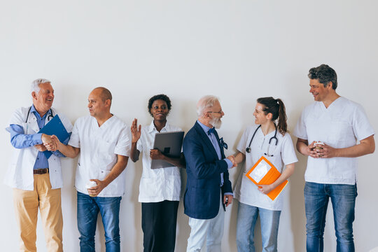 Smiling healthcare workers shaking hands in a row against white wall