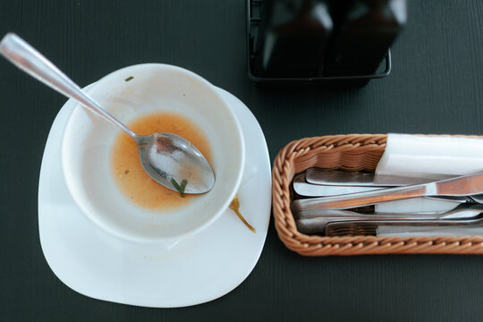 Empty Soup Bowl With Spoon Hot Chili Pepper And Cutlery. Finished soup plate sits near a wicker basket with restaurant cutlery