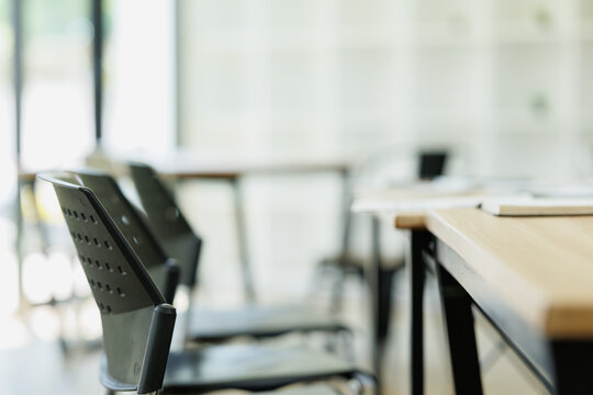 Empty chairs and wooden tables in a modern minimalist workspace, providing a quiet and organized environment for study, collaboration, or productive work