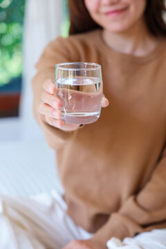 Vertical closeup image of a woman holding and serving a glass of drinking water