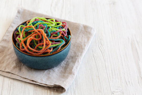 Colorful Spaghetti Jelly Candies Sprinkled with Sugar in a Bowl, side view. Copy space.