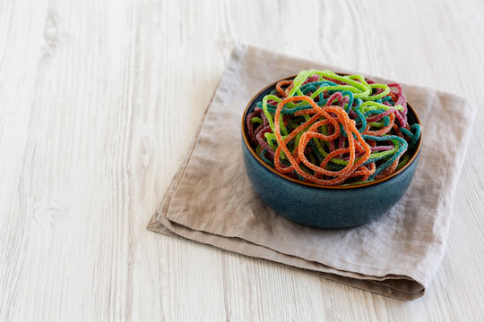 Colorful Spaghetti Jelly Candies Sprinkled with Sugar in a Bowl, side view. Copy space.