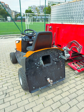 Lawn mower parked near sports field during daytime with tools in background
