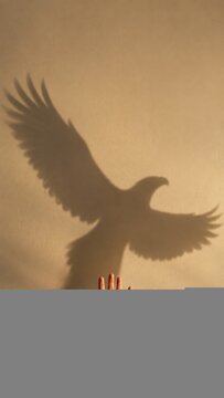 Human hand casting a soaring eagle shadow against a warm beige wall with copy space, for personal growth and motivation campaigns