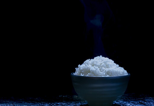 Steaming white rice in ceramic bowl dark background minimal style Asian cuisine hot fresh cooked healthy food comfort meal simple aromatic delicious isolated