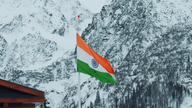 4K shot of Indian tricolor flag waving in front of snowy Himalayan mountain peaks during the winter season as seen from Manali in Himachal Pradesh, India. Indian flag waves at high altitudes.
