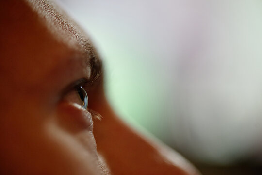 Extreme close up of young adult Caucasian man staring intently at screen representing video game addiction. Visual concept for digital wellbeing campaigns and screen time awareness