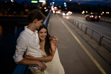 Fototapeta premium Young couple embracing on urban bridge at night