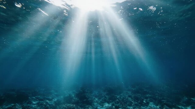 Sunlight beams piercing deep blue ocean water showing seabed textures during daytime