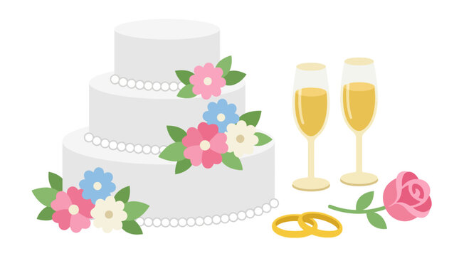 Wedding cake adorned with sugar flowers sits near two glasses of champagne, golden rings, and a pink rose on a plain background.