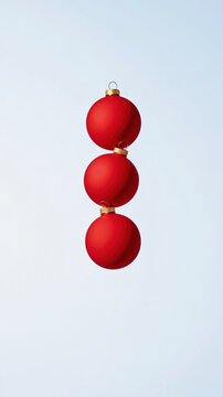 Three red glass baubles stacked in a vertical column, featuring a high-gloss finish and silver caps for festive holiday banners with copy space