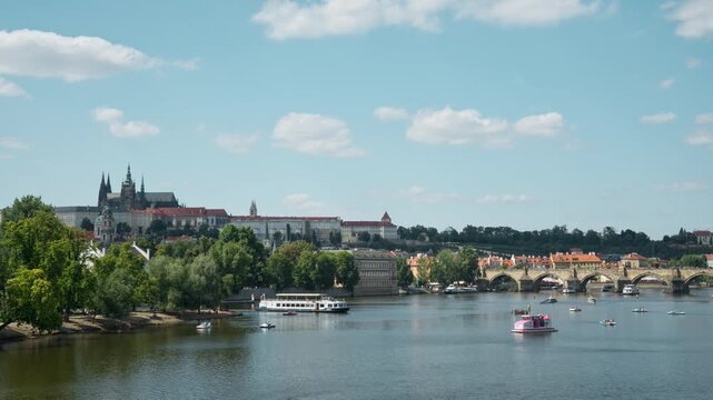 Tourists ride pedal boats and cruise ships along the Vltava River in Prague. The historical Charles Bridge and Prague Castle stand under a bright summer sky in this European travel scene.