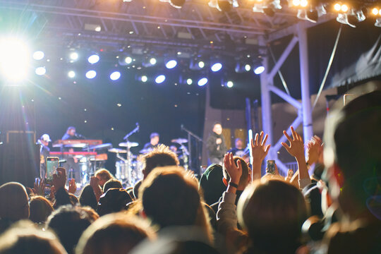 Crowd raising hands at live outdoor concert at night