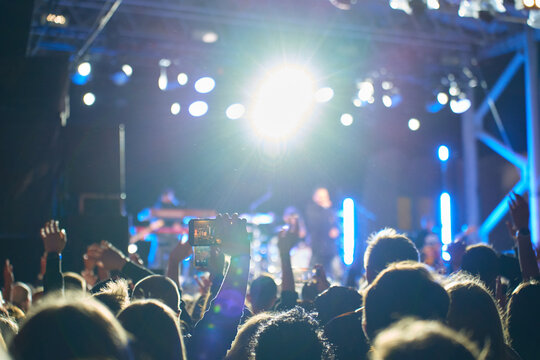 People watches a live outdoor concert at night, record the stage on a smartphone