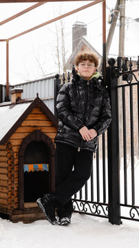 Young person standing by a dog house in a snowy yard during winter