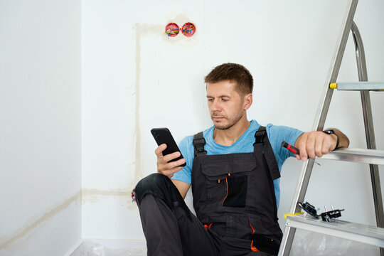 Electrician checking smartphone during renovation work
