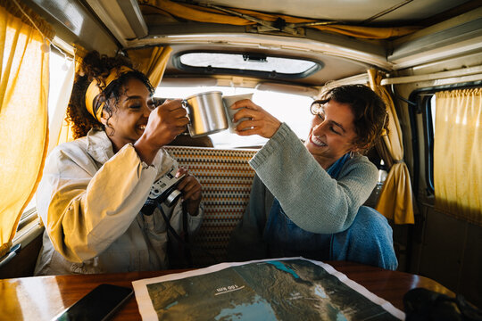 Friends toast mugs in a camper van during a road trip