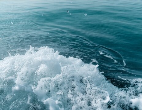close up of white sea foam bubbles and splashes with blue ocean water background