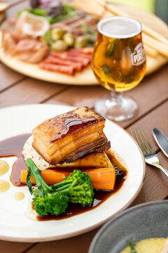 Delicious Pork Belly Served on a Bed of Vegetables With a Refreshing Beer