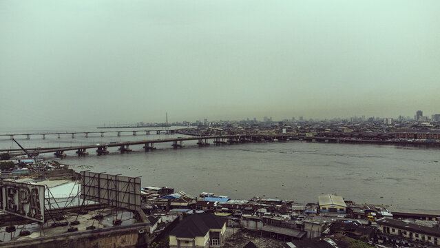 Aerial view of the Carter Bridge spanning the Lagos Lagoon with dense urban development and rooftops in the foreground in Lagos, Lagos, Nigeria.