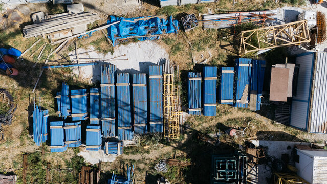 Aerial view of TASYAPI construction site featuring stacks of blue metal beams, construction materials, and equipment on a dirt ground in Kuzmin, Vojvodina, Serbia.