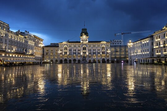 Illuminated square Piazza Unit&agrave; d'Italia, Town Hall, Palazzo Communale, with reflection, dramatic clouds, blue hour, old town, Trieste, Friuli-Venezia Giulia region, Italy