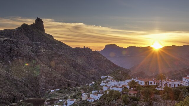 Dusk, sunset, sun as star, Tejeda, village, white houses, red roofs, Massif Central, Roque Bentayga, mountain landscape, blue sky, orange clouds, grey clouds, Gran Canaria, Canary Islands, Spain