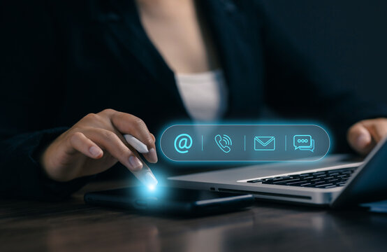 Business professional using smartphone and laptop with virtual contact icons for email, phone and messaging, illustrating digital communication, customer service and online connectivity.